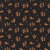 Fabric with desert-themed pattern including horses, cacti, and mountains on a black background.